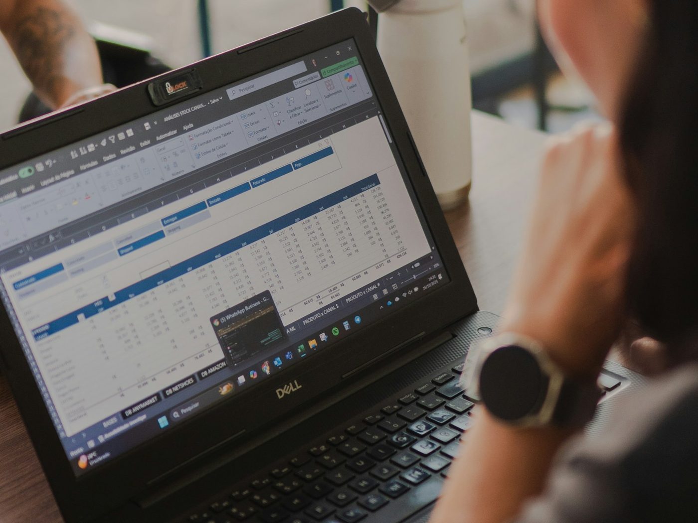 A woman working on a laptop with spreadsheet data